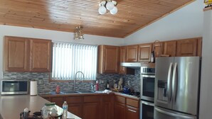 Una cocina moderna con armarios de madera, un refrigerador de acero inoxidable y una isla central.