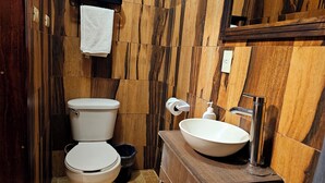 A bathroom with a toilet, sink, and wooden wall paneling. - Arte Sano Hotel San Cristobal (San Cristóbal de las Casas)