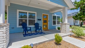 A blue house with a yellow door, two blue chairs, and a small garden.