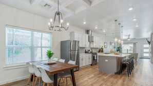 A spacious kitchen with a wooden dining table, white chairs, and a central island with bar stools.