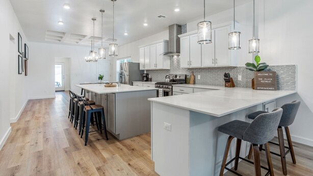 A modern kitchen with white cabinetry, a large island, and pendant lighting.