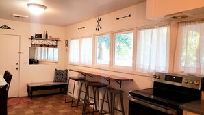 A kitchen with a stove, bar stools, a bench, and a window with curtains. - Old Farm Land by Willamette River Oak Trees Bike Path Shopping Restaurants (Eugene)