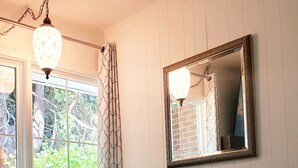 A room with a dark green sofa, a white pillow with text, a large mirror, and a hanging light fixture. - Old Farm Land by Willamette River Oak Trees Bike Path Shopping Restaurants (Eugene)