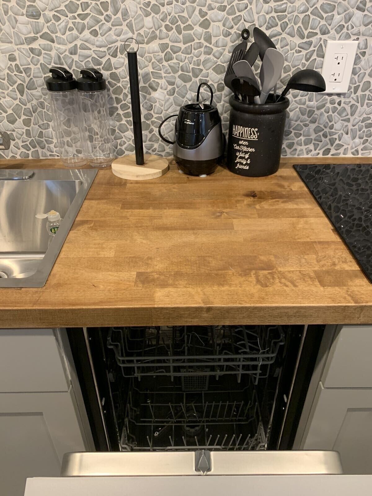 Una cocina con mostrador de madera, cafetera, hervidor y un portalapaces.