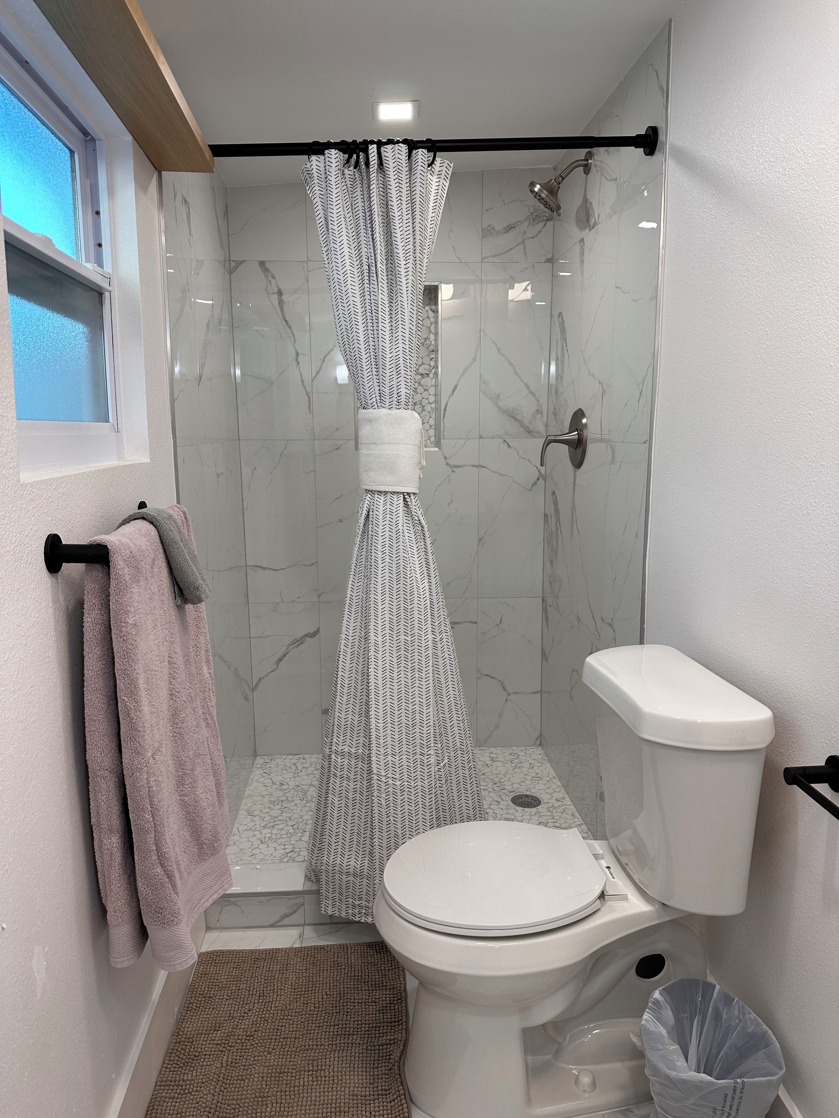 Une salle de bain avec une douche, des toilettes et une fenêtre.