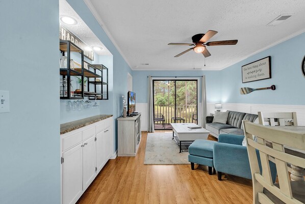 A modern kitchen with white cabinets, a wooden countertop, and a ceiling fan.