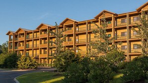 Een meerlaags hotel met balkons en een verzorgd gazon.