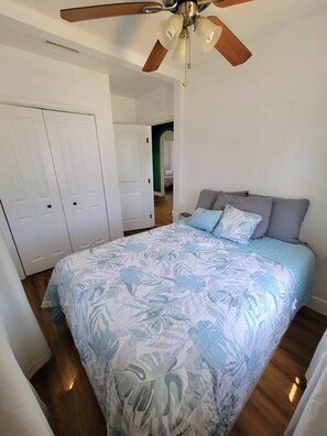 Un dormitorio con una cama, un ventilador de techo y un armario.
