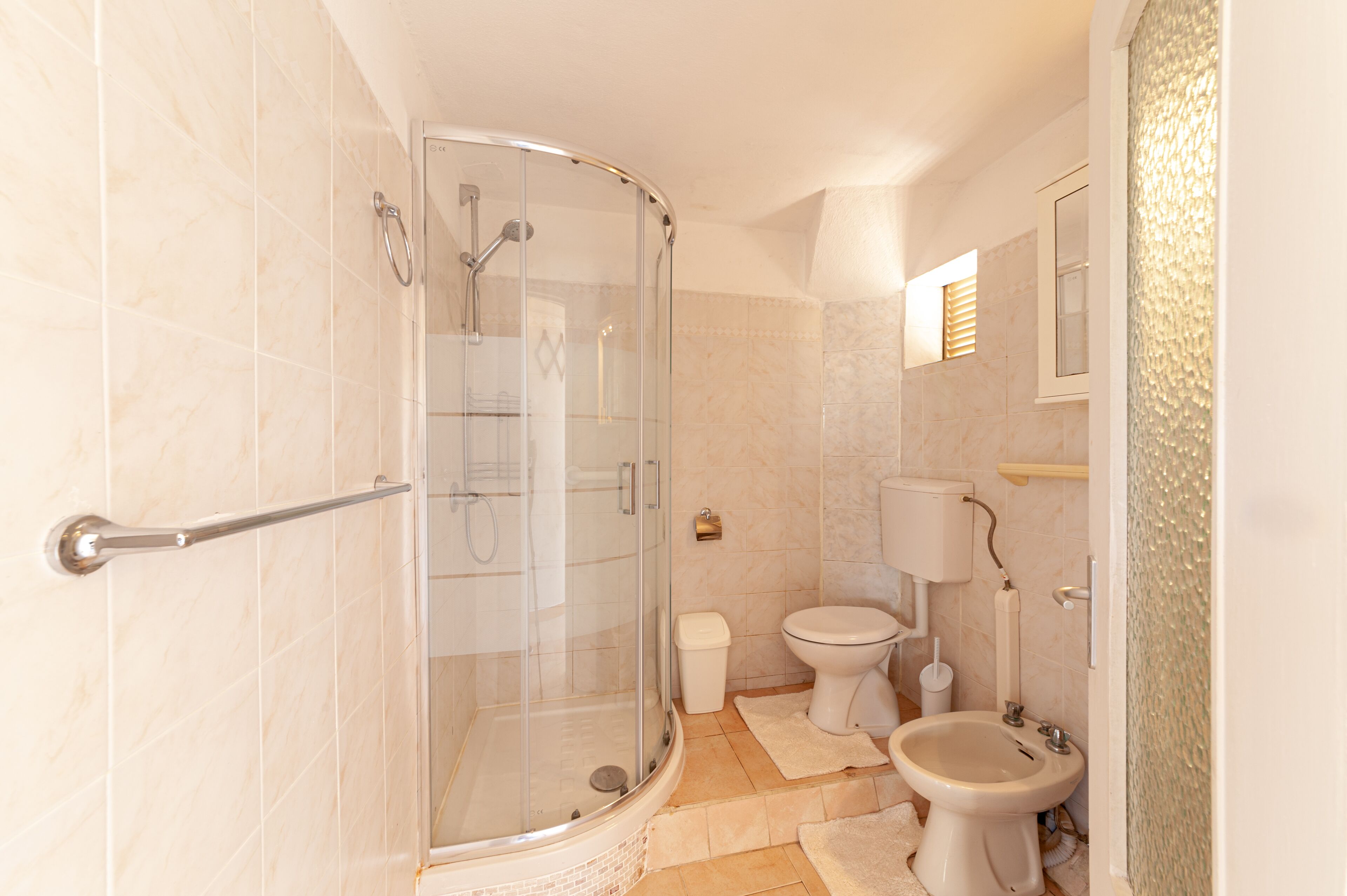 Un baño con ducha de mampara de vidrio, inodoro y bidé.
