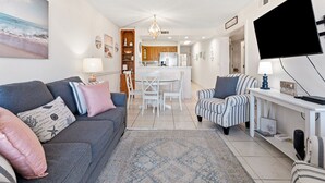 A living room with a sofa, armchairs, a TV, and a dining area with a table and chairs. - Step into your oceanfront paradise (North Myrtle Beach)