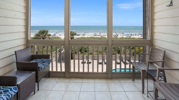 A balcony with a view of the beach, wicker furniture, and a pool. - Step into your oceanfront paradise (North Myrtle Beach)
