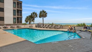 A pool area with lounge chairs, a pool, and a view of the ocean. - Step into your oceanfront paradise (North Myrtle Beach)