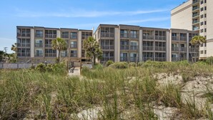 A beachfront hotel with multiple floors, balconies, and a sandy beach area in front. - Step into your oceanfront paradise (North Myrtle Beach)
