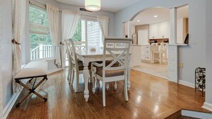 A dining area with a wooden table and chairs, a bench, and a view of the kitchen and deck. - 15% off 5 nights or more (Ocean Pines)
