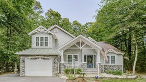 A two-story house with a stone foundation, a garage, and a front porch with a small garden. - 15% off 5 nights or more (Ocean Pines)