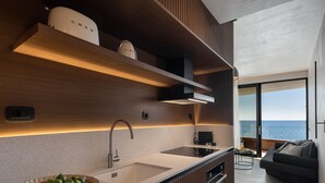 Une cuisine moderne dotée d’un grand îlot central, d’appareils électroménagers intégrés et offrant une vue sur la mer.