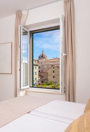 A bedroom with a large window, a bed, and a view of buildings outside. - 48 Rooms Split (Split)