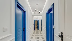 A hallway with blue doors, a patterned floor, and a chandelier.