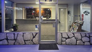 A hotel entrance with a stone facade, a reception desk, and a display of postcards. - BIGGS NU-VU MOTEL (Biggs Junction)
