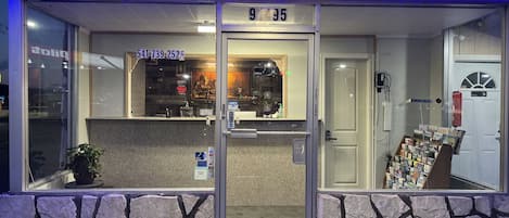 A hotel entrance with a stone facade, a reception desk, and a display of postcards.