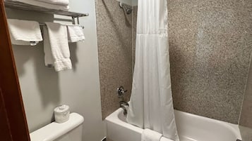A bathroom with a toilet, a bathtub with a shower curtain, and a towel rack with folded towels.
