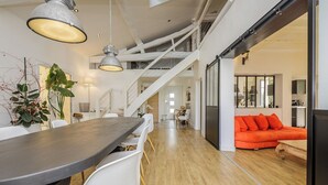 A modern interior with a dining area, staircase, and a bright orange sofa.
