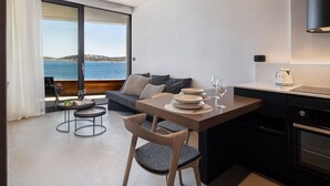 Ett modernt kök med matplats, utsikt över havet och en mysig sittgrupp med soffa och fåtöljer.