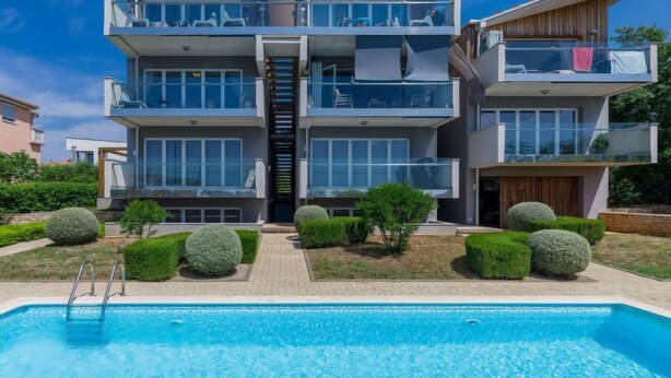 Un moderno edificio residenziale a più piani con una piscina in primo piano.