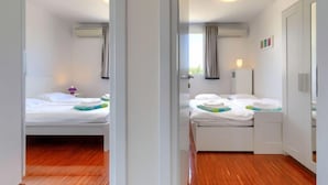 Una camera d'albergo moderna con due letti, pavimento in legno e vista sull'esterno.