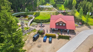 An aerial view of a building labeled "HARRACHOY" with a red roof, surrounded by greenery and a parking area with two cars. - Harrachov Central Nest by Interhome (Harrachov)