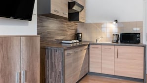 A modern kitchen with wooden cabinets, a built-in microwave, a coffee maker, and a flat-screen TV mounted on the wall. - Harrachov Central Nest by Interhome (Harrachov)