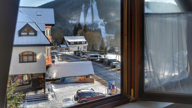 A view from a window overlooking a town with a mountain in the background, a parking lot, and a building with a sign that reads "MEDICAL". - Harrachov Central Nest by Interhome (Harrachov)