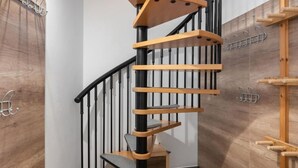 Eine Wendeltreppe mit Holzbodenstufen und schwarzen Geländern, die zu einer oberen Etage führt.