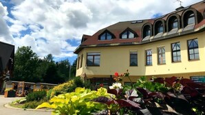 Ein Gebäude mit gelber Fassade, zahlreichen Fenstern und einem geneigten Dach.