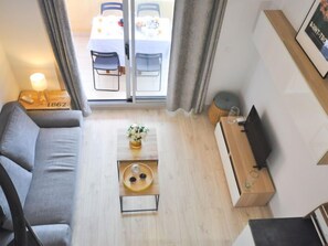 Uma sala de estar moderna com sofá, mesa de centro, televisão e área de jantar com mesa e cadeiras.