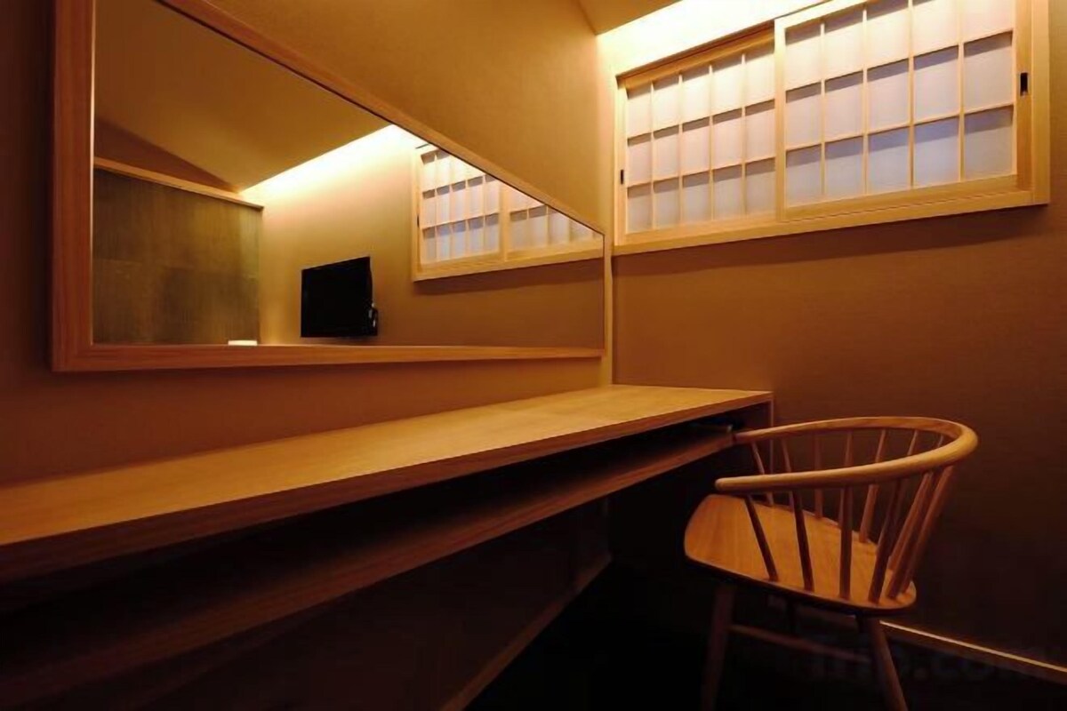 A bathroom with a mirror, a sink, and a chair.