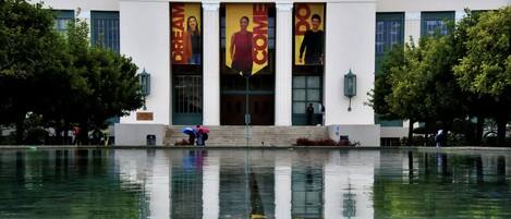 The facade of Pasadena City College with large banners and a reflective water feature in front.