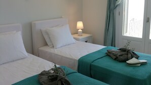 Een hotelkamer met twee bedden, een nachtkastje met een lamp, een raam met gordijnen en uitzicht op buiten.
