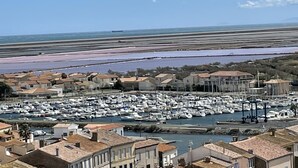 A coastal marina with numerous boats docked, surrounded by residential buildings with terracotta roofs. - Authentic wooden chalet with sea view sleeps 4 (Gruissan)