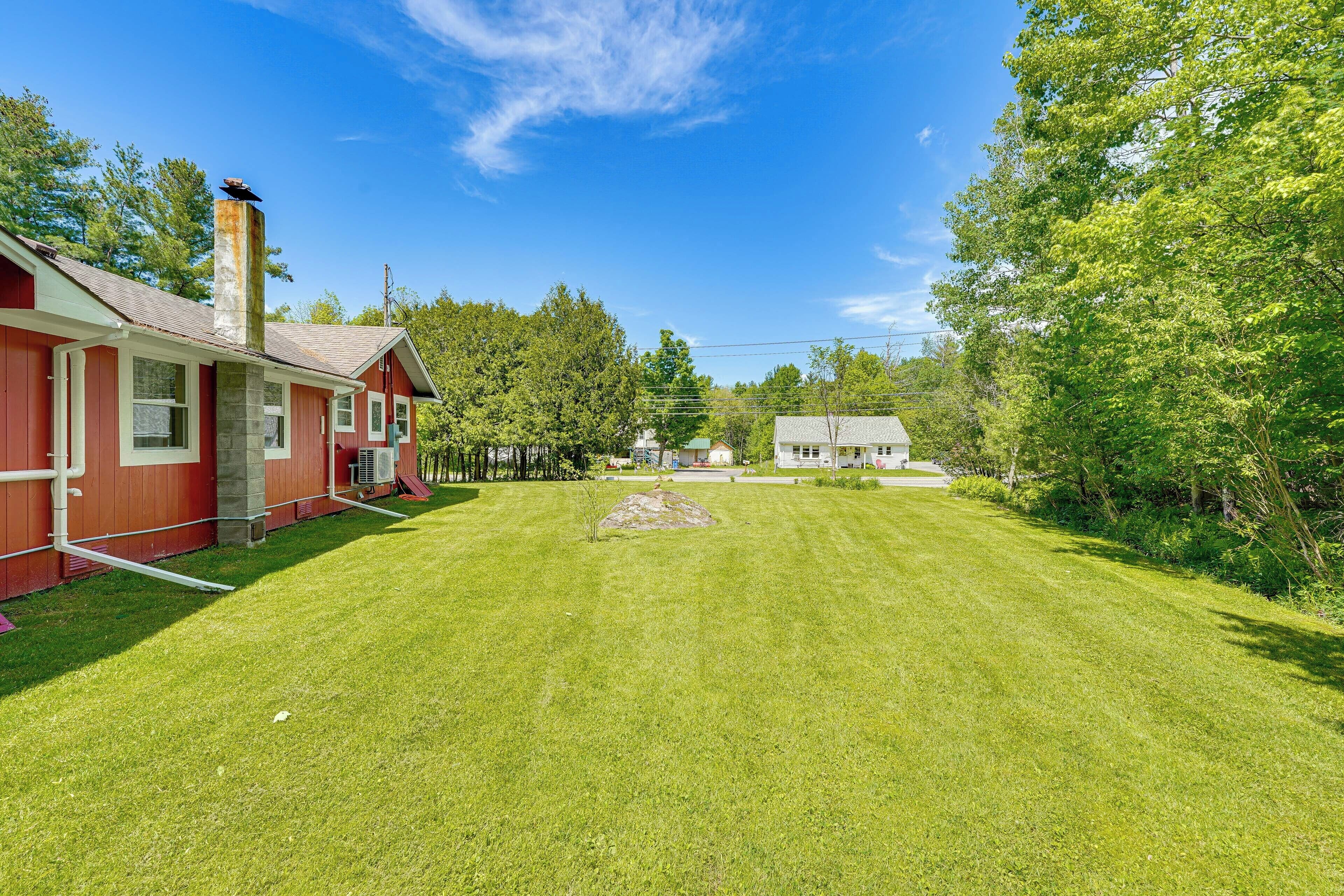 A red building with a chimney, a well-maintained lawn, and trees in the background.