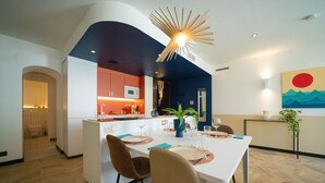 A modern kitchen with white cabinets, a microwave, and a dining area with a white table and chairs. - Roma Divine: home cinema, luxury city center (Nimes)