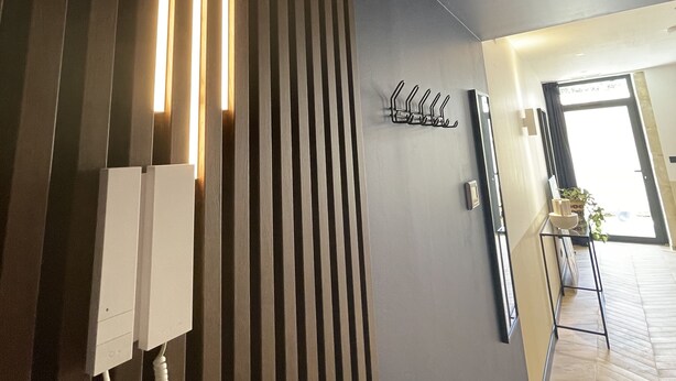 A modern interior with a wooden slat wall, a telephone, and a metal rack. - Roma Divine: home cinema, luxury city center (Nimes)