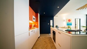 A modern kitchen with white cabinets, a wooden herringbone floor, and a dark ceiling. - Roma Divine: home cinema, luxury city center (Nimes)
