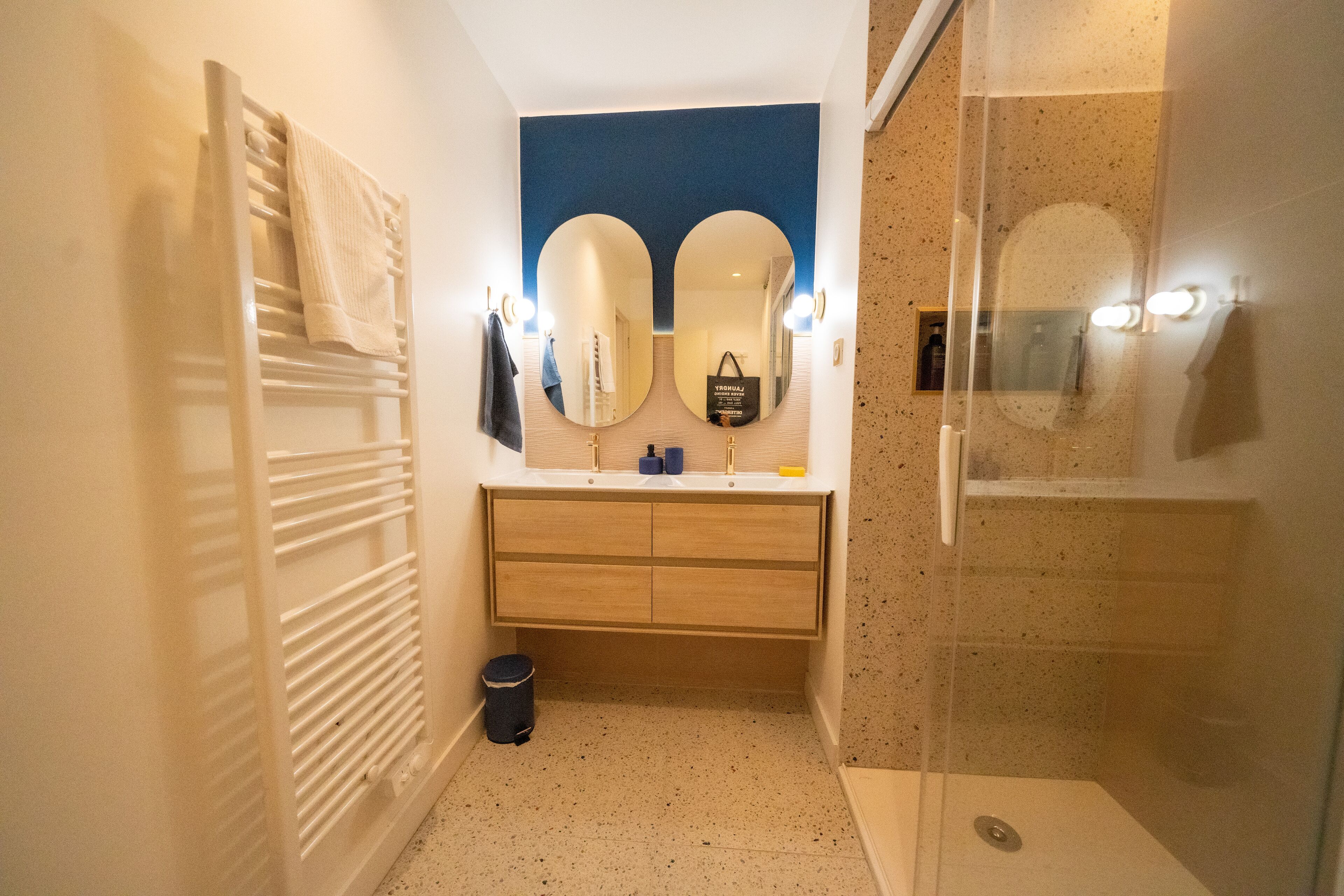 A bathroom with a mirror, towel rack, sink, and shower.