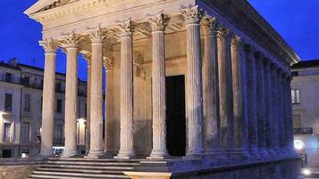 A classical building with a portico supported by columns, featuring a grand staircase leading to the entrance.