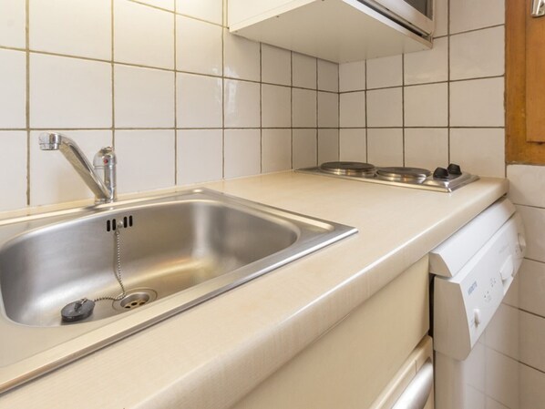A kitchen with a stainless steel sink, a faucet, a stove with a control panel, and a dishwasher.
