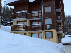 Un hotel de varios pisos con balcones y ventanas amplias, rodeado de nieve.
