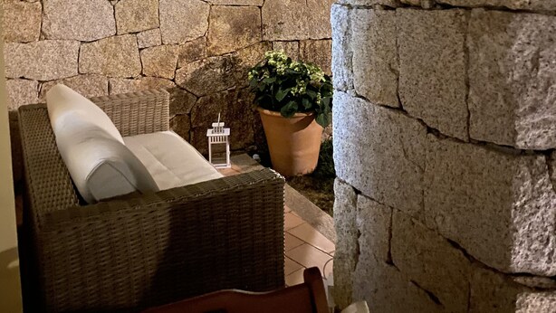 A stone-walled interior with a wicker sofa and a potted plant.
