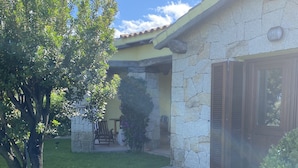 A house with a stone facade, a tiled roof, and a well-maintained lawn.