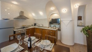 A modern kitchen with white tiled walls, wooden cabinets, and a built-in stove.